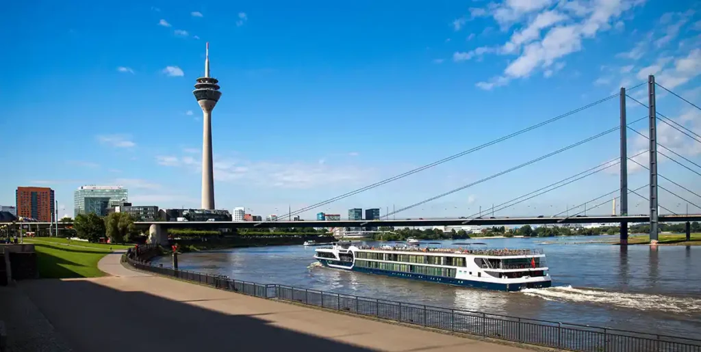 Kreuzfahrtschiff startet vom Hafen Düsseldorf vor Fernsehturm am Rhein